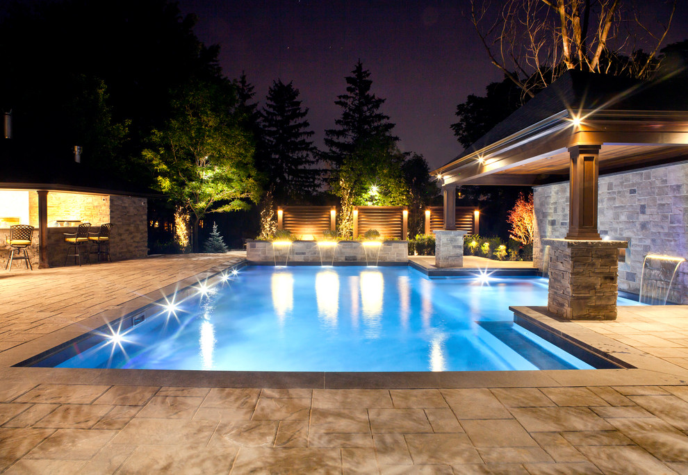 Inspiration for a large modern backyard rectangular lap pool in Toronto with a water feature and stamped concrete.