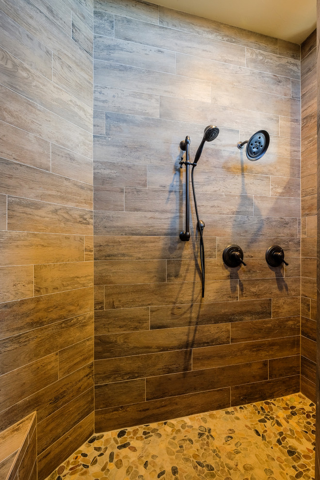 Inspiration for a mid-sized country 3/4 bathroom in Denver with shaker cabinets, dark wood cabinets, a corner shower, a two-piece toilet, brown tile, multi-coloured tile, stone tile, beige walls, porcelain floors, a trough sink and granite benchtops.