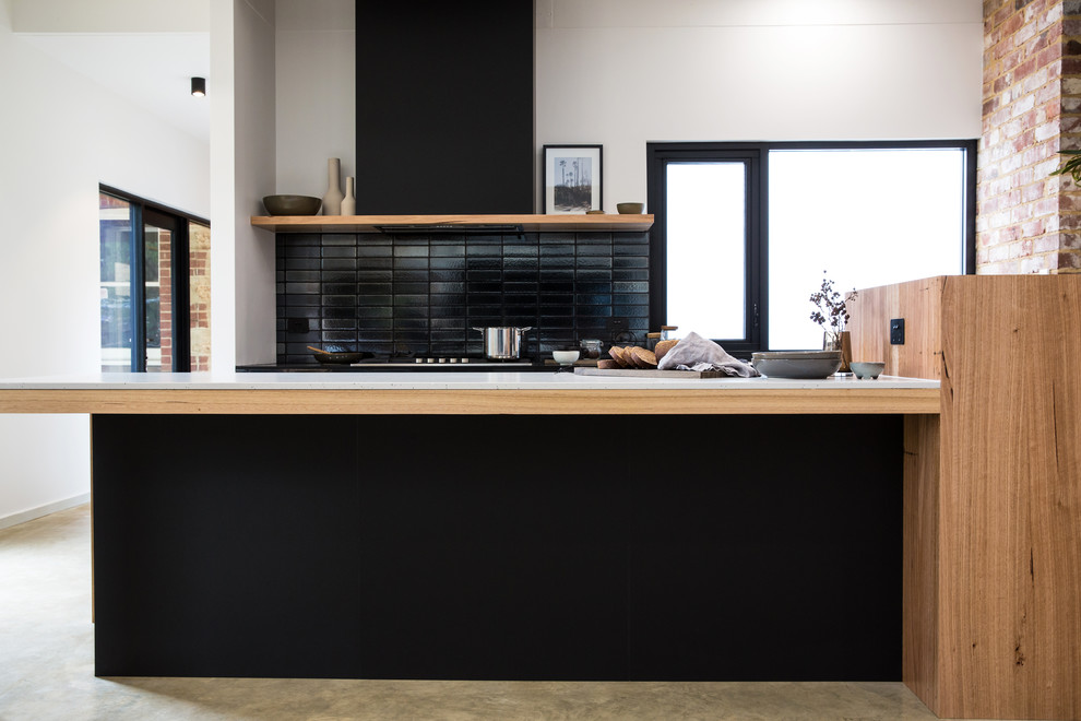This is an example of an expansive industrial galley kitchen pantry in Other with a double-bowl sink, shaker cabinets, grey cabinets, solid surface benchtops, black splashback, subway tile splashback, stainless steel appliances, concrete floors, with island, grey floor and white benchtop.