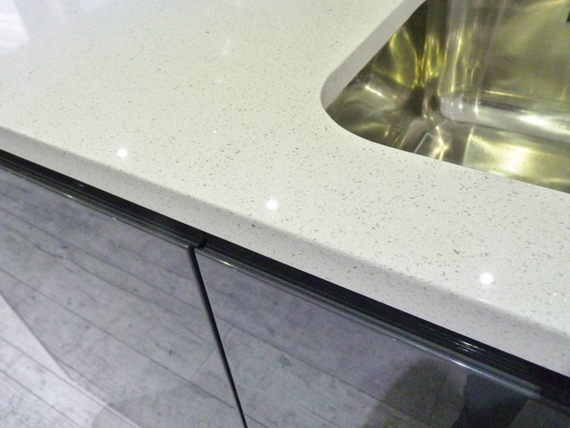 Gloss lacquered 'graphite' handleless kitchen with white quartz worktops contemporaneo-cocina