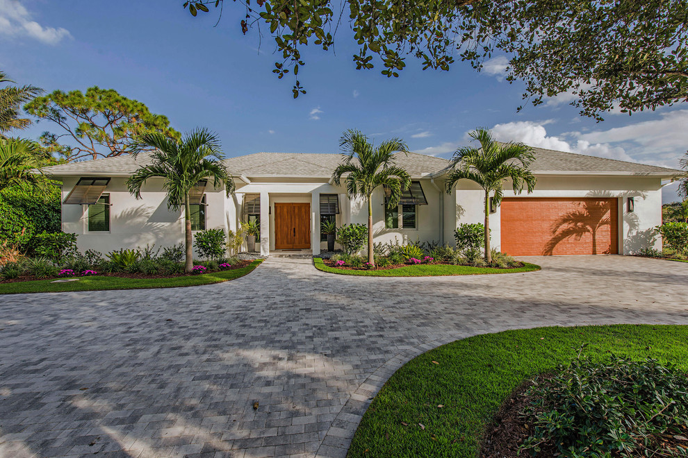 This is an example of a large tropical one-storey stucco white exterior in Miami with a hip roof.