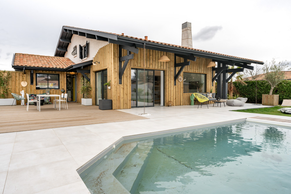 Diseño de piscina marinera grande rectangular en patio trasero con paisajismo de piscina y entablado