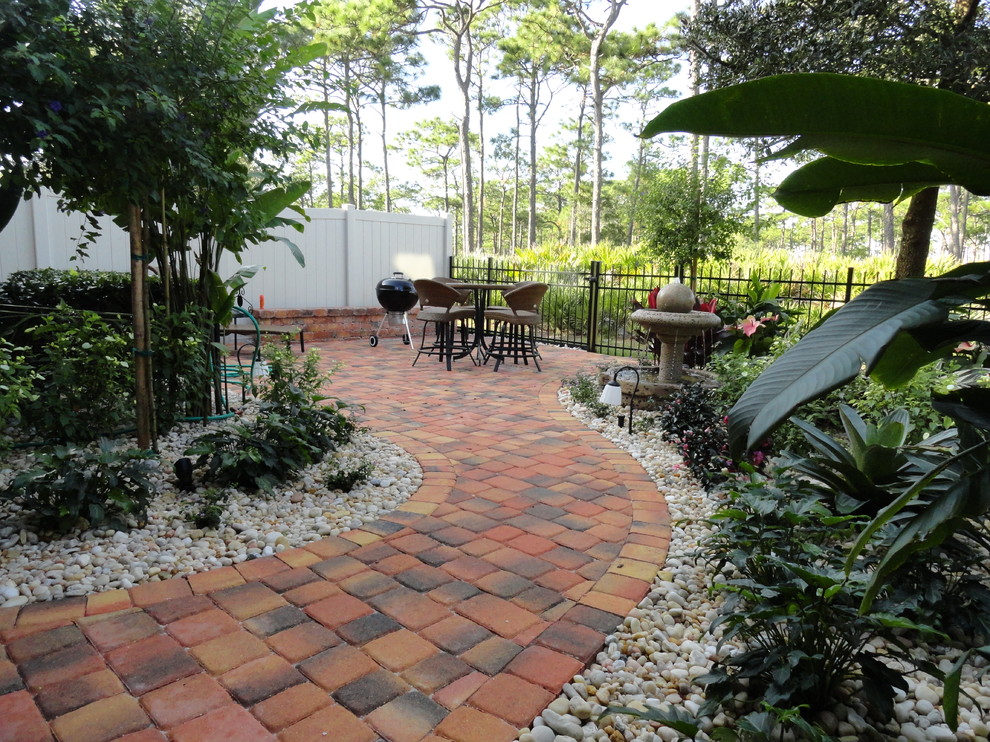 Inspiration for a mid-sized tropical backyard patio in Orlando with a water feature, brick pavers and a roof extension.