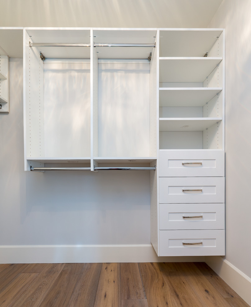 Walk-in closet - mid-sized transitional gender-neutral medium tone wood floor walk-in closet idea with shaker cabinets and white cabinets