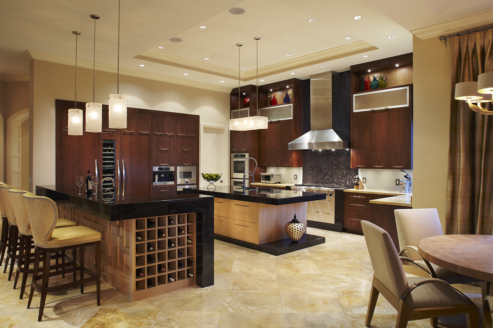 Photo of a large contemporary u-shaped eat-in kitchen in Miami with flat-panel cabinets, dark wood cabinets, granite benchtops, an undermount sink, white splashback, subway tile splashback, panelled appliances, limestone floors and multiple islands.