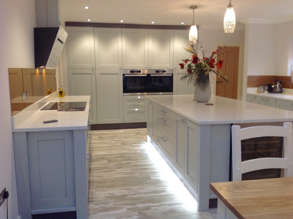 Design ideas for a large contemporary galley eat-in kitchen in Cambridgeshire with shaker cabinets, grey cabinets, quartzite benchtops, metallic splashback, with island, a double-bowl sink, mirror splashback, stainless steel appliances and medium hardwood floors.