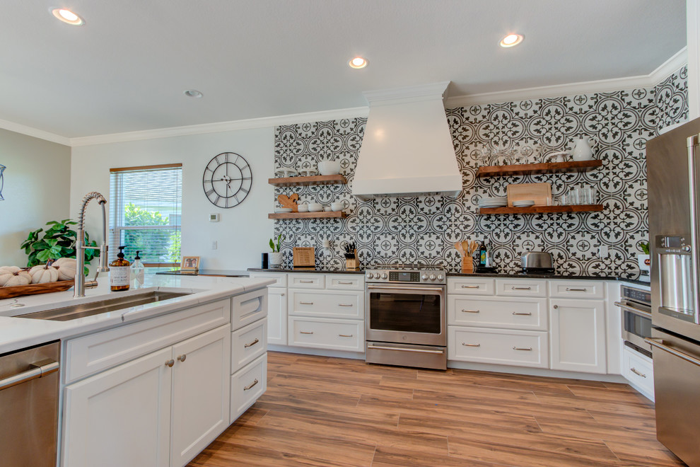 Eat-in kitchen - large transitional l-shaped ceramic tile and brown floor eat-in kitchen idea with an undermount sink, shaker cabinets, white cabinets, quartz countertops, multicolored backsplash, ceramic backsplash, stainless steel appliances, an island and white countertops