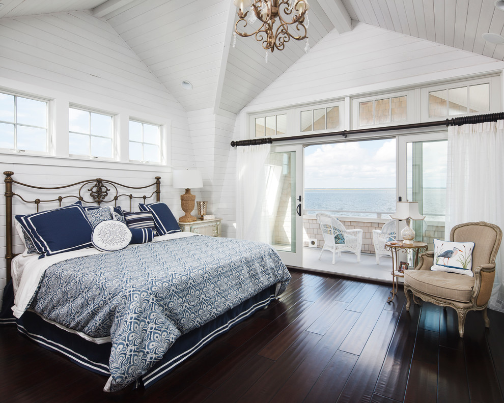 This is an example of a mid-sized beach style master bedroom in New York with white walls, dark hardwood floors, brown floor and no fireplace.