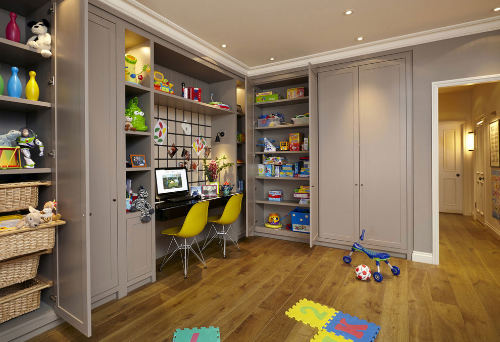 This is an example of a transitional gender-neutral kids' playroom for kids 4-10 years old in London with medium hardwood floors and grey walls.