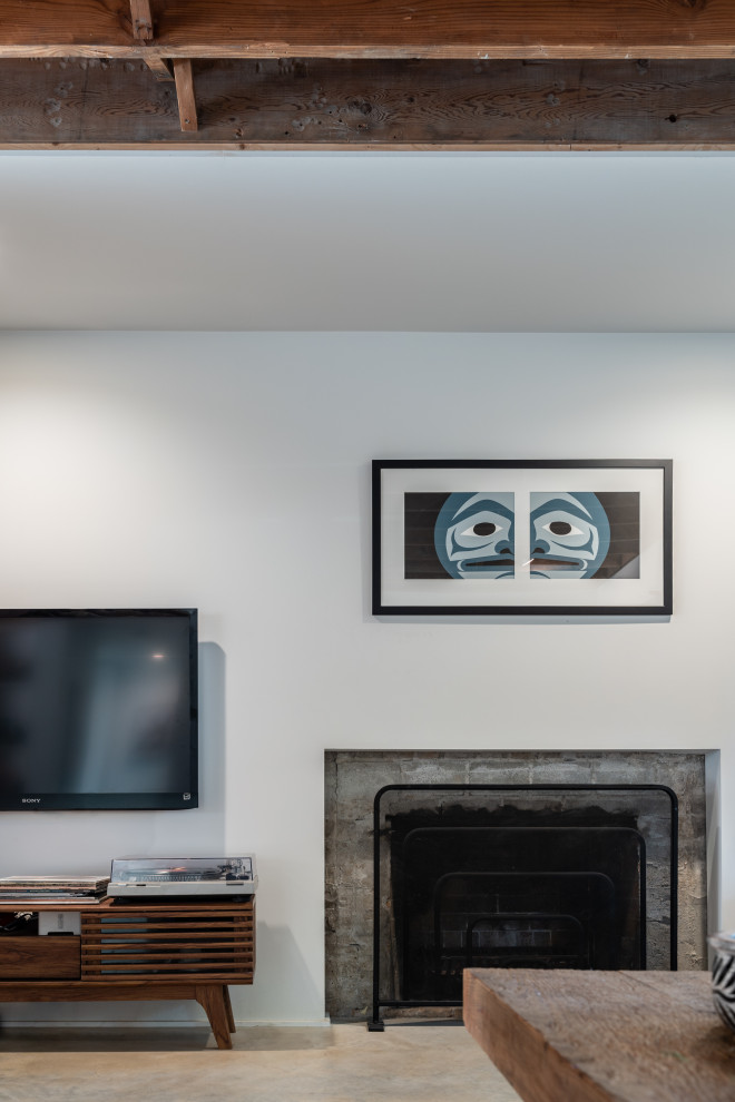 Example of a mid-sized urban open concept concrete floor family room design in Vancouver with white walls, a standard fireplace, a brick fireplace and a wall-mounted tv
