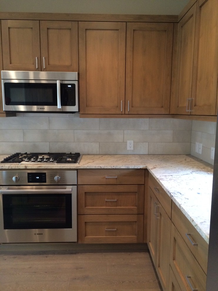 Kitchen - small transitional l-shaped medium tone wood floor kitchen idea with an undermount sink, shaker cabinets, medium tone wood cabinets, granite countertops, beige backsplash, porcelain backsplash, stainless steel appliances and an island