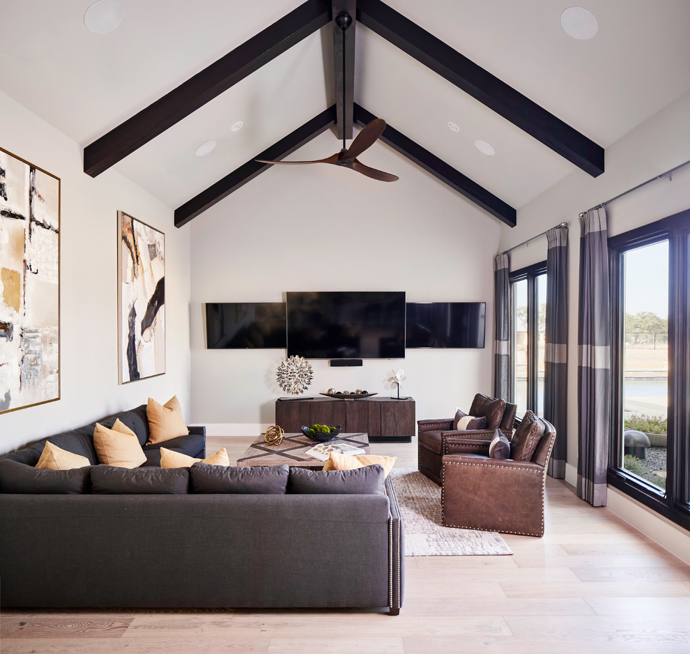 Home theater - transitional light wood floor home theater idea in Austin with white walls and a wall-mounted tv