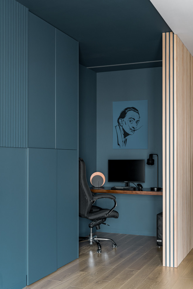 Inspiration för mellanstora moderna hemmabibliotek, med blå väggar, mellanmörkt trägolv, ett inbyggt skrivbord och beiget golv
