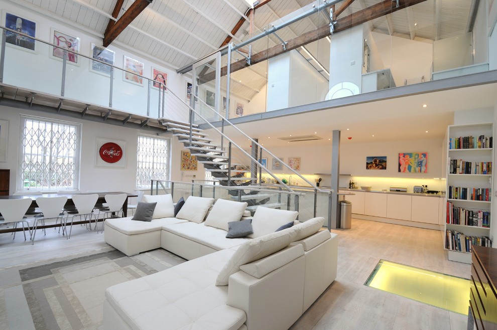 This is an example of an industrial formal living room in London with white walls and light hardwood floors.