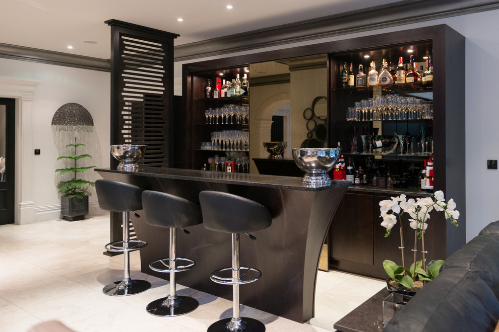 This is an example of a large contemporary u-shaped seated home bar in Manchester with flat-panel cabinets, dark wood cabinets, granite benchtops and porcelain floors.