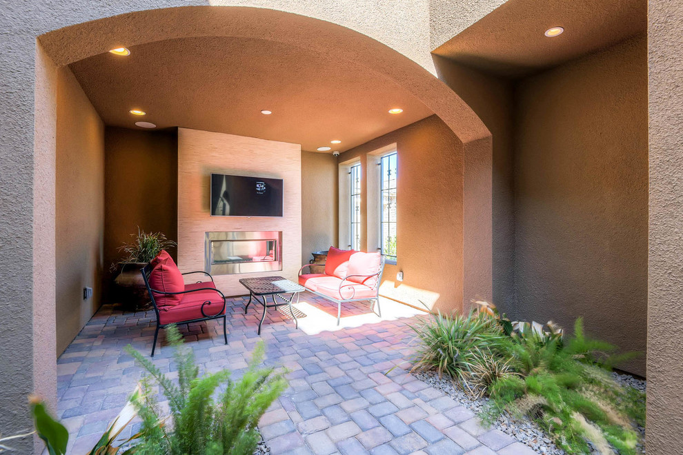 Inspiration for a mid-sized transitional front yard verandah in Las Vegas with a fire feature, brick pavers and a roof extension.