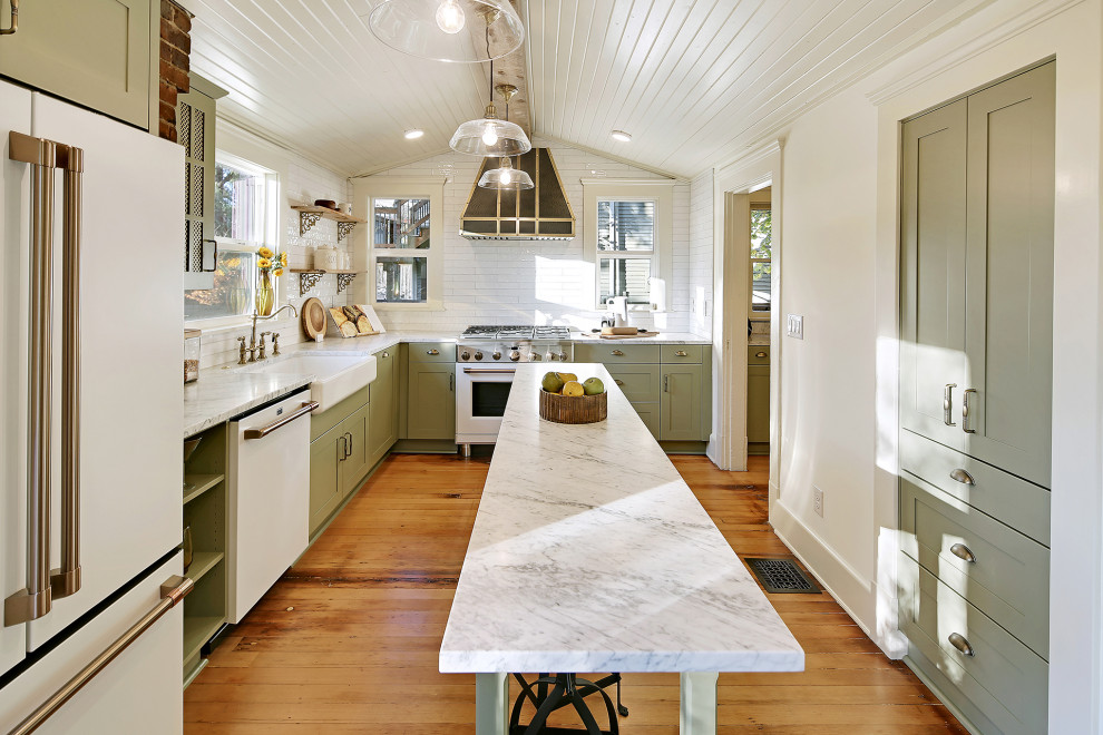 Large arts and crafts separate kitchen in Seattle with a farmhouse sink, green cabinets, white splashback, white appliances, medium hardwood floors, with island, brown floor and multi-coloured benchtop.