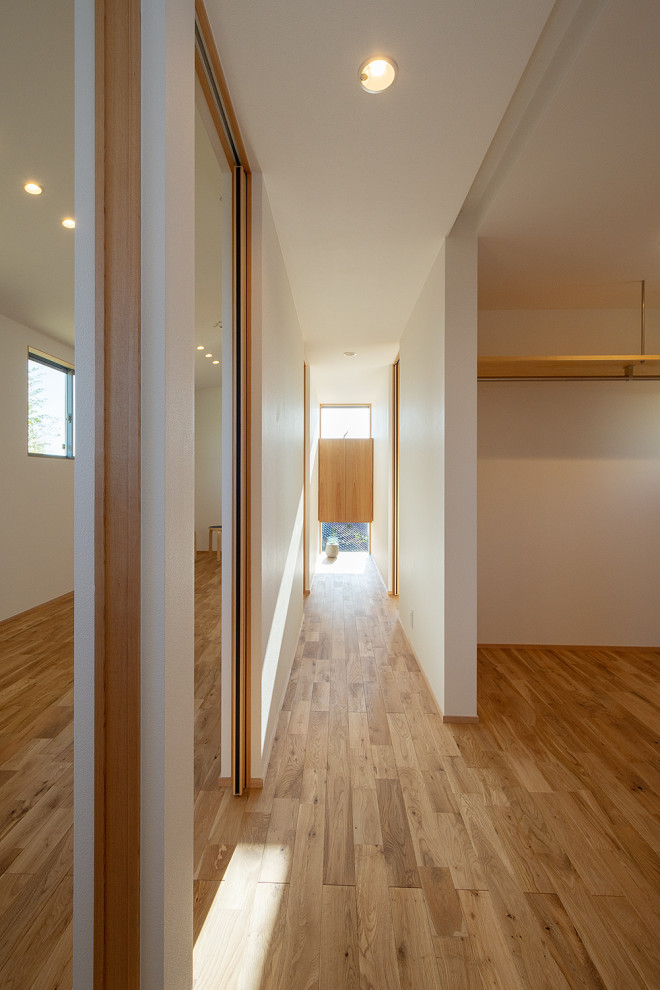 Réalisation d'un couloir nordique de taille moyenne avec un mur blanc, un sol en bois brun, un sol marron, un plafond en papier peint et du papier peint.