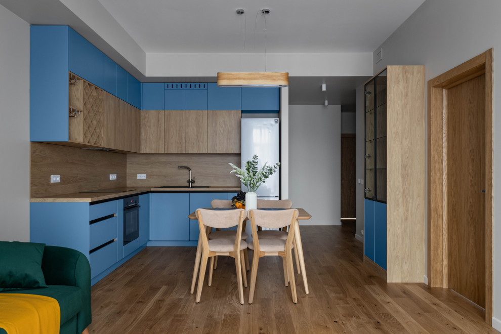Exempel på ett mellanstort minimalistiskt brun brunt kök, med en enkel diskho, släta luckor, blå skåp, laminatbänkskiva, brunt stänkskydd, stänkskydd i trä, svarta vitvaror, mellanmörkt trägolv och brunt golv