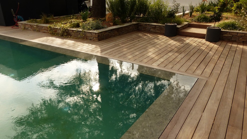 This is an example of a mid-sized contemporary side yard rectangular infinity pool in Montpellier with decking.