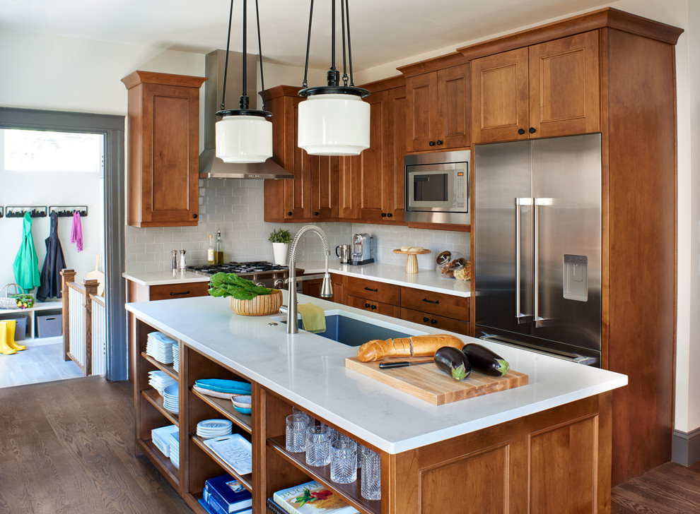 Design ideas for a small arts and crafts l-shaped eat-in kitchen in Denver with an undermount sink, shaker cabinets, medium wood cabinets, quartz benchtops, grey splashback, subway tile splashback, stainless steel appliances, medium hardwood floors, with island and brown floor.