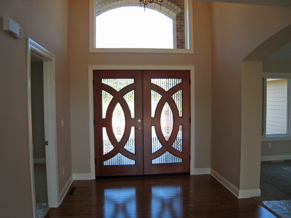 Front door - large transitional dark wood floor and brown floor front door idea in Milwaukee with beige walls and a glass front door