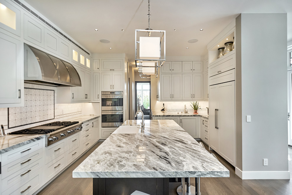 Inspiration for a large contemporary u-shaped open plan kitchen in San Francisco with a farmhouse sink, white cabinets, marble benchtops, white splashback, marble splashback, with island, shaker cabinets, panelled appliances, dark hardwood floors and brown floor.
