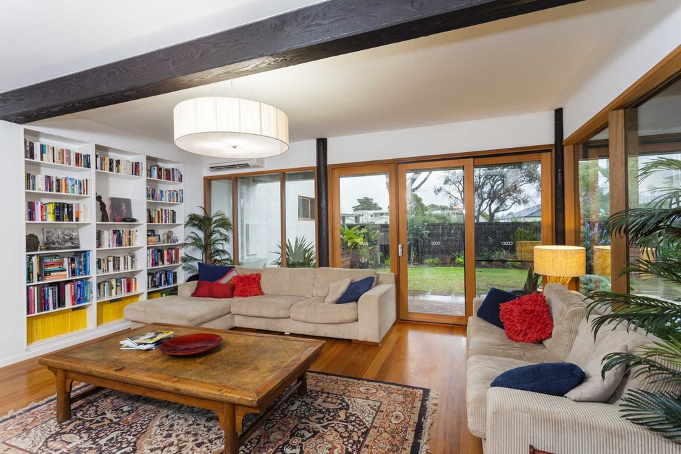 Mid-sized midcentury open concept living room in Melbourne with a library, white walls and medium hardwood floors.
