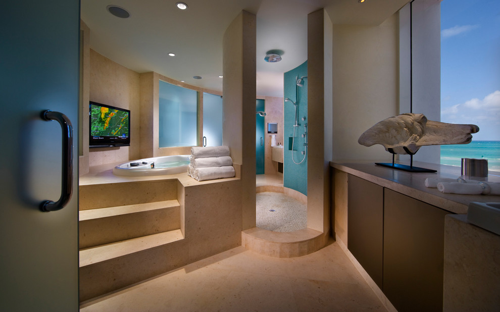 This is an example of an expansive tropical master bathroom in Miami with flat-panel cabinets, dark wood cabinets, a drop-in tub, a corner shower, beige tile, limestone floors, a drop-in sink, granite benchtops, beige floor and an open shower.