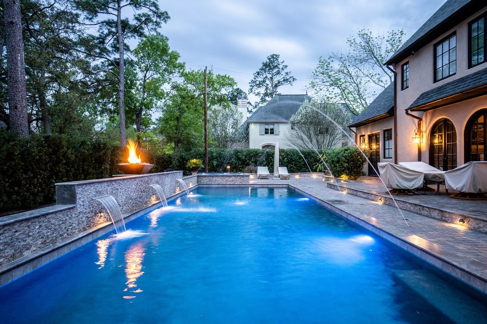 This is an example of a large mediterranean backyard rectangular pool in Houston with a pool house and concrete pavers.