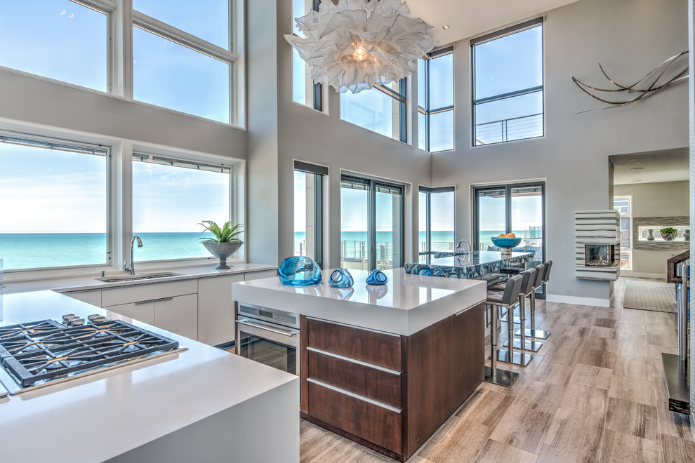 Design ideas for an expansive modern l-shaped open plan kitchen in Chicago with an undermount sink, flat-panel cabinets, white cabinets, quartzite benchtops, blue splashback, stone slab splashback, panelled appliances, limestone floors, multiple islands and brown floor.