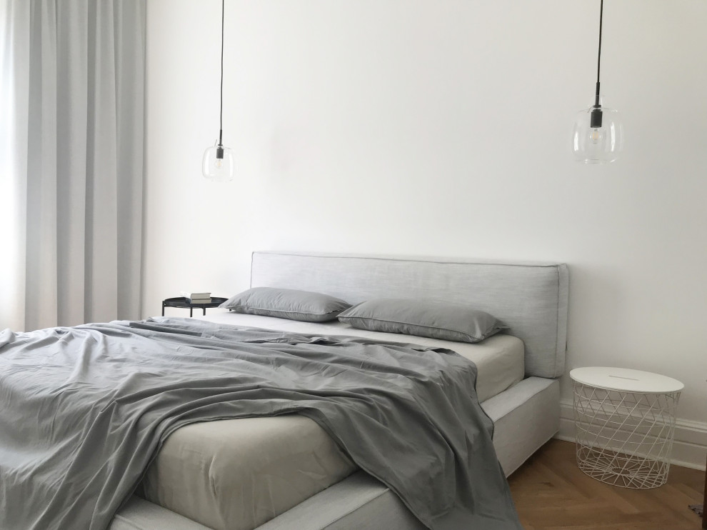 Diseño de dormitorio principal y gris y blanco actual de tamaño medio con suelo de madera clara