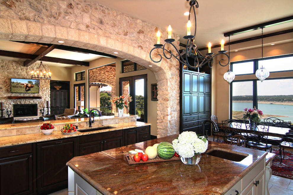 This is an example of a large mediterranean u-shaped eat-in kitchen in Austin with raised-panel cabinets, medium wood cabinets, granite benchtops, beige splashback, mosaic tile splashback, panelled appliances, travertine floors and with island.