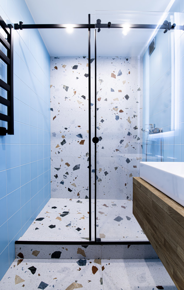 Modern inredning av ett litet brun brunt badrum med dusch, med släta luckor, skåp i mellenmörkt trä, en dusch i en alkov, flerfärgad kakel, keramikplattor, blå väggar, klinkergolv i keramik, ett fristående handfat, träbänkskiva, flerfärgat golv och dusch med skjutdörr