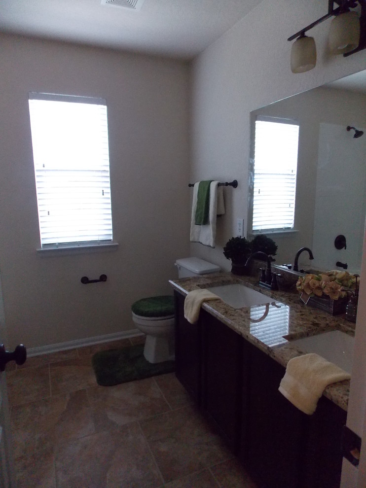 Photo of a mid-sized traditional kids bathroom in Austin with an undermount sink, flat-panel cabinets, medium wood cabinets, granite benchtops, an alcove tub, a shower/bathtub combo, a two-piece toilet, multi-coloured tile, ceramic tile, beige walls and ceramic floors.