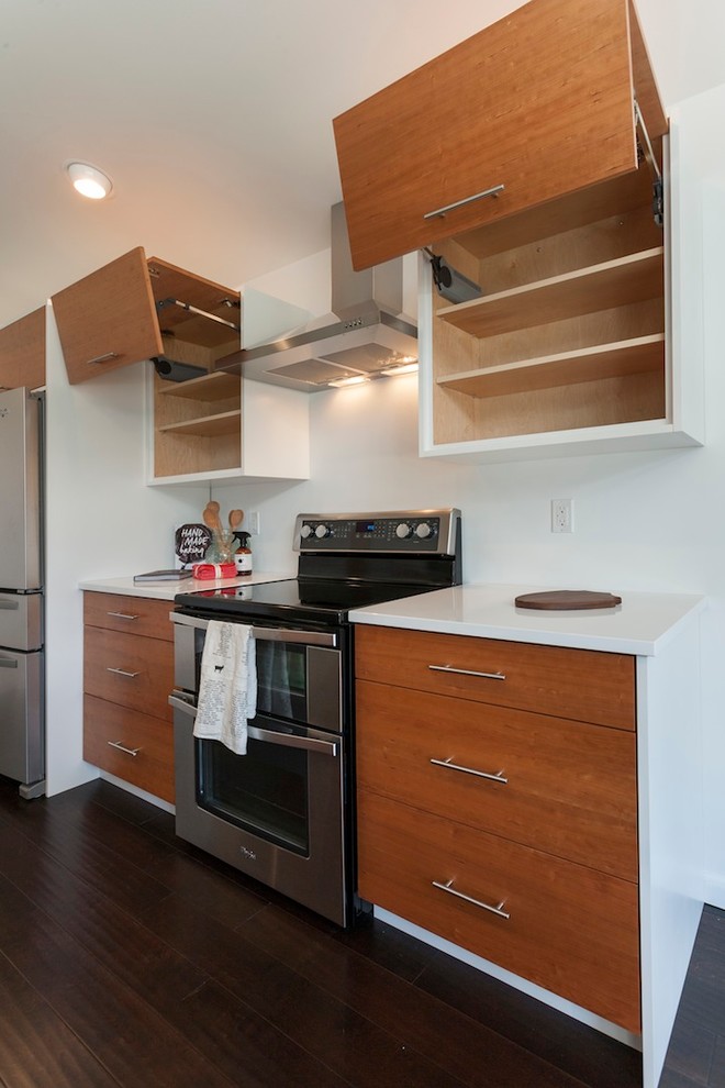 This is an example of a mid-sized midcentury galley eat-in kitchen in Other with a double-bowl sink, flat-panel cabinets, light wood cabinets, solid surface benchtops, white splashback, stainless steel appliances, dark hardwood floors and with island.