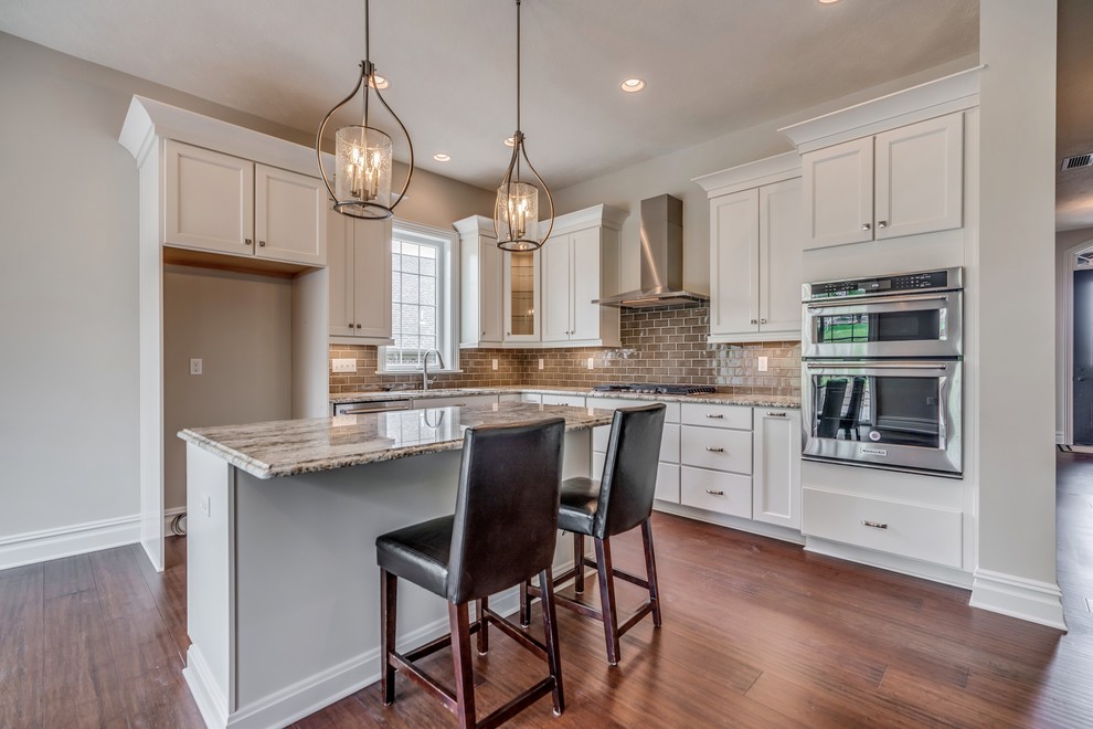 Eat-in kitchen - transitional l-shaped bamboo floor and brown floor eat-in kitchen idea with an undermount sink, flat-panel cabinets, white cabinets, granite countertops, brown backsplash, subway tile backsplash, stainless steel appliances, an island and brown countertops