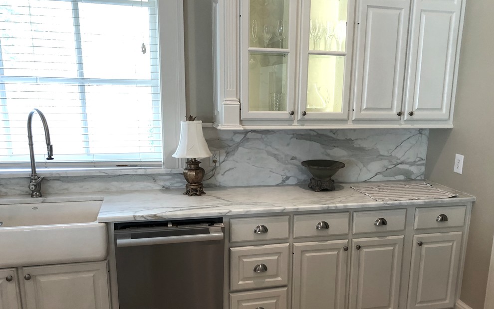 Photo of a traditional kitchen in New Orleans with marble benchtops, white splashback, marble splashback, with island, beige floor and white benchtop.