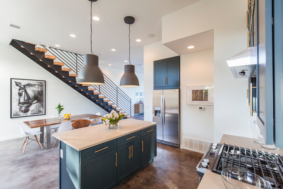 Large contemporary eat-in kitchen in Austin with an undermount sink, shaker cabinets, blue cabinets, quartz benchtops, grey splashback, stone tile splashback, stainless steel appliances, concrete floors and with island.