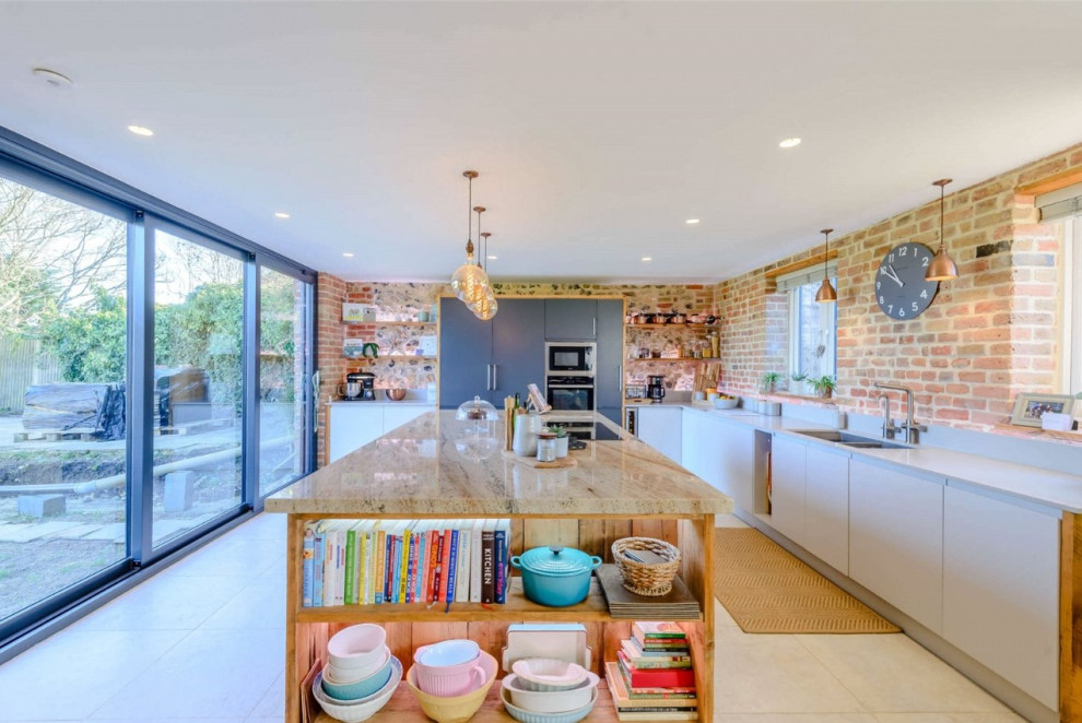Inspiration for a large urban grey and white l-shaped open plan kitchen in Kent with a double-bowl sink, flat-panel cabinets, grey cabinets, granite worktops, grey splashback, engineered quartz splashback, integrated appliances, porcelain flooring, an island, grey floors, multicoloured worktops and a feature wall.
