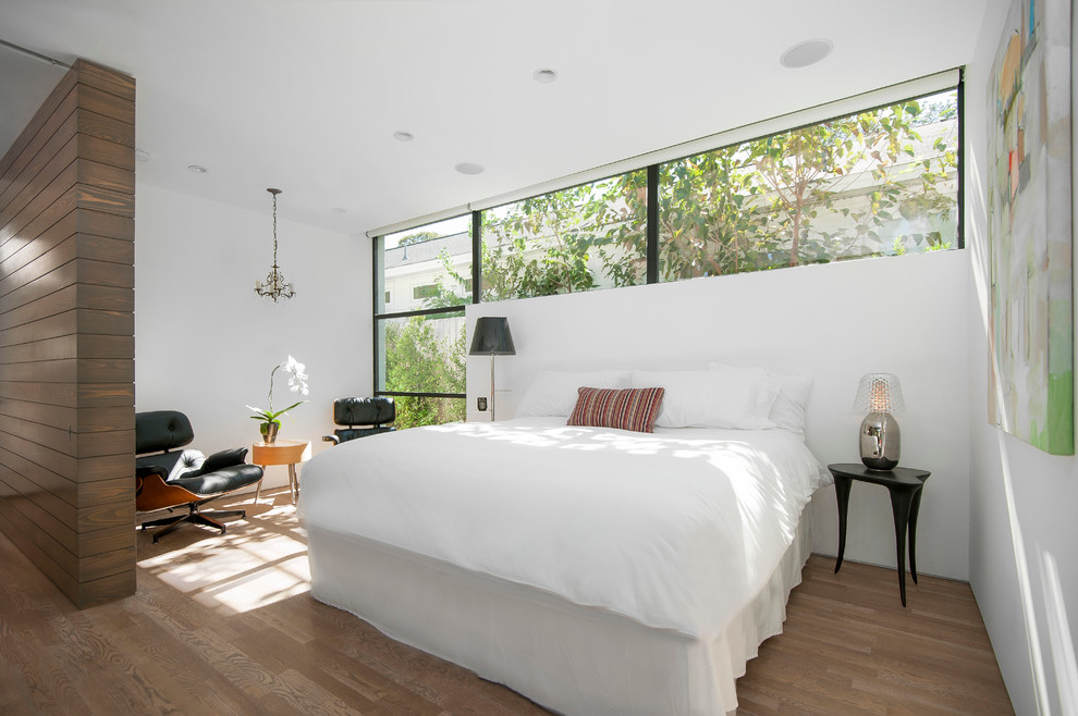 Design ideas for a contemporary bedroom in Austin with white walls and medium hardwood floors.