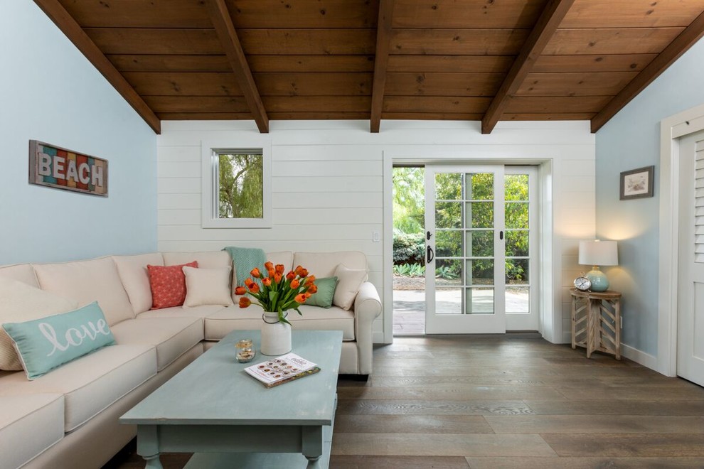 Small beach style living room in Santa Barbara with blue walls, medium hardwood floors, no fireplace and brown floor.