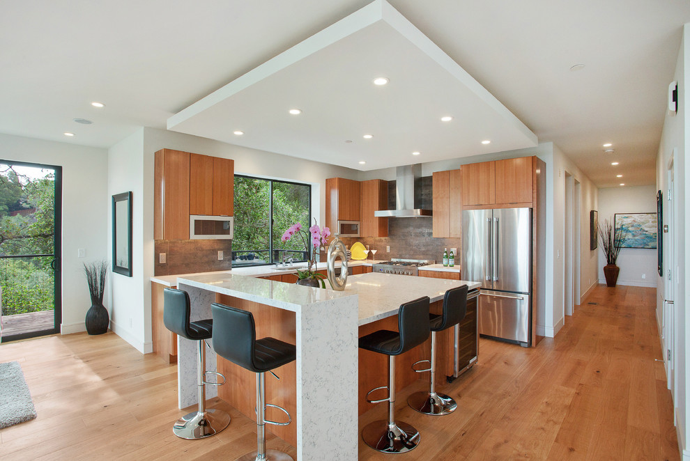 Photo of a contemporary l-shaped kitchen in San Francisco with flat-panel cabinets, medium wood cabinets, grey splashback, stainless steel appliances, medium hardwood floors and with island.