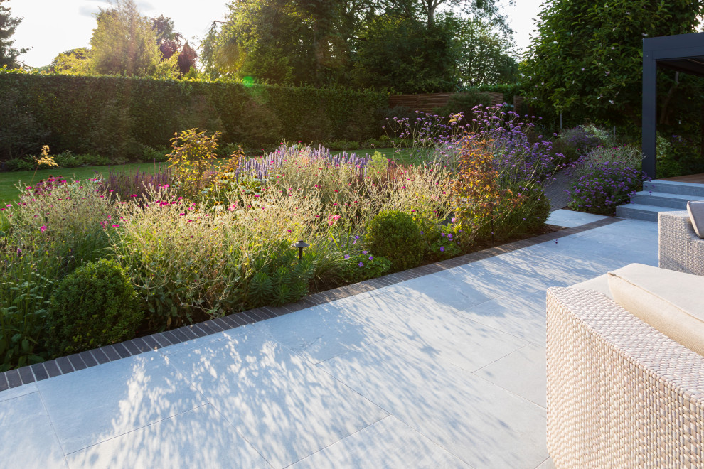 Aménagement d'un jardin à la française arrière contemporain de taille moyenne et l'été avec un massif de fleurs, une exposition ensoleillée et des pavés en brique.