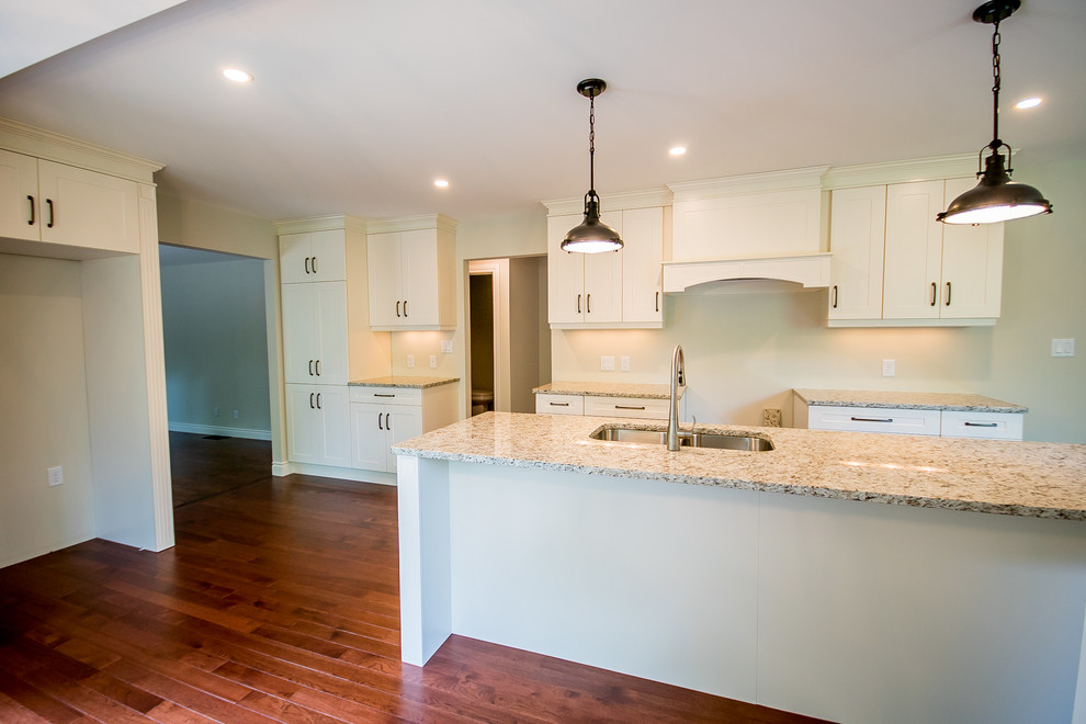Inspiration for a large transitional single-wall medium tone wood floor eat-in kitchen remodel in Toronto with an undermount sink, shaker cabinets, white cabinets, granite countertops and an island