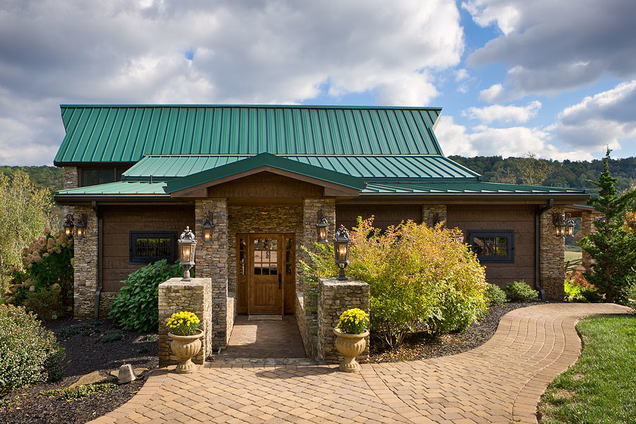 This is an example of a large country two-storey brown house exterior in Nashville with stone veneer, a hip roof and a metal roof.