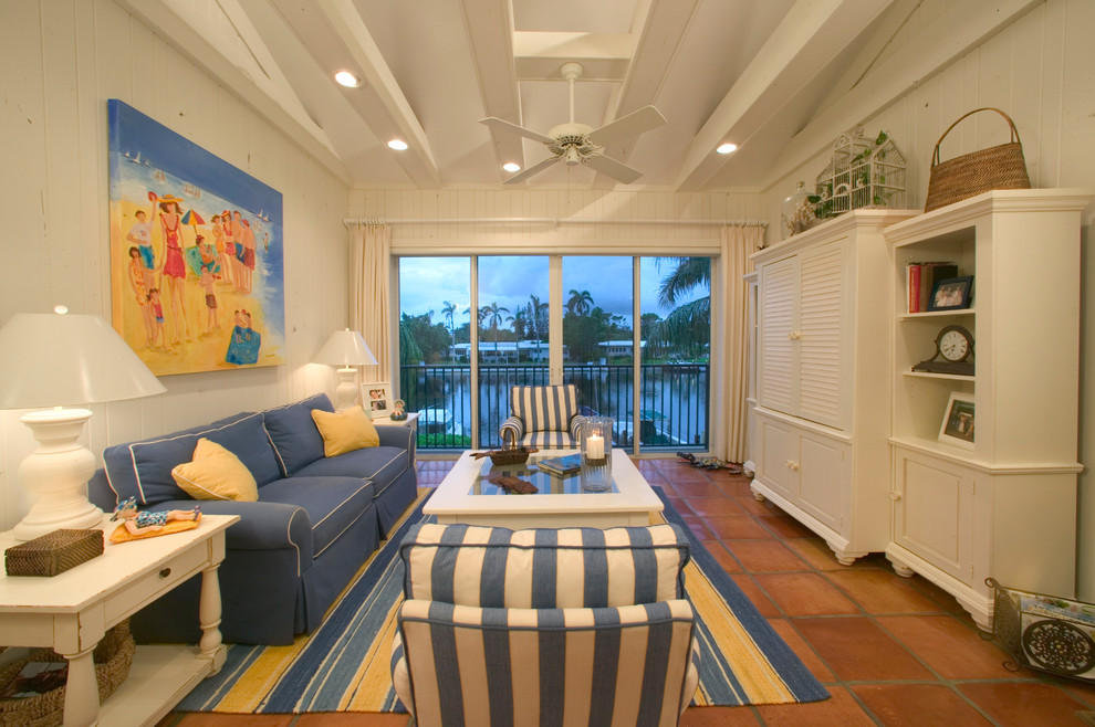 Photo of a beach style living room in Miami with terra-cotta floors and a concealed tv.