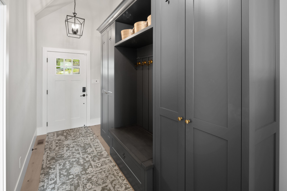 Foto de hall abovedado clásico con paredes grises, suelo de madera clara, puerta simple, puerta blanca y suelo marrón