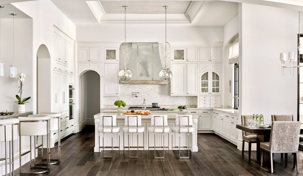 Inspiration for a mediterranean u-shaped open plan kitchen in Phoenix with multiple islands, an undermount sink, beaded inset cabinets, white cabinets, white splashback, mosaic tile splashback, panelled appliances, dark hardwood floors, brown floor, grey benchtop and recessed.