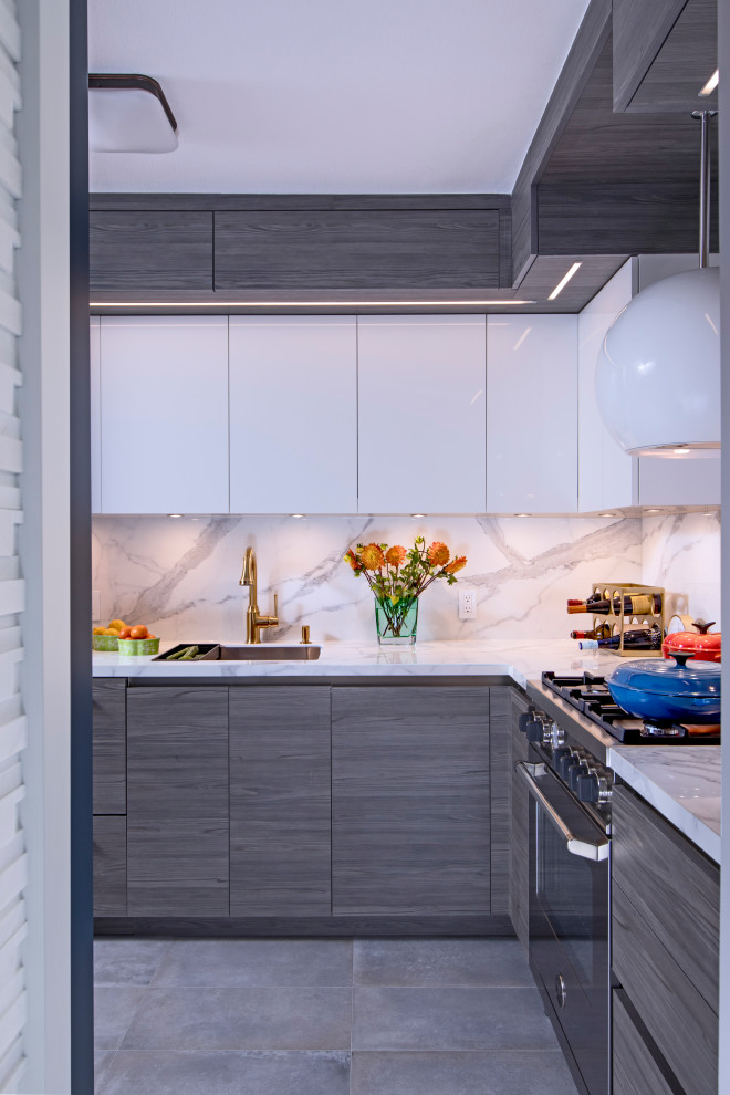 Photo of a small contemporary galley separate kitchen in New York with an undermount sink, flat-panel cabinets, grey cabinets, white splashback, stone slab splashback, stainless steel appliances, porcelain floors, grey floor and white benchtop.